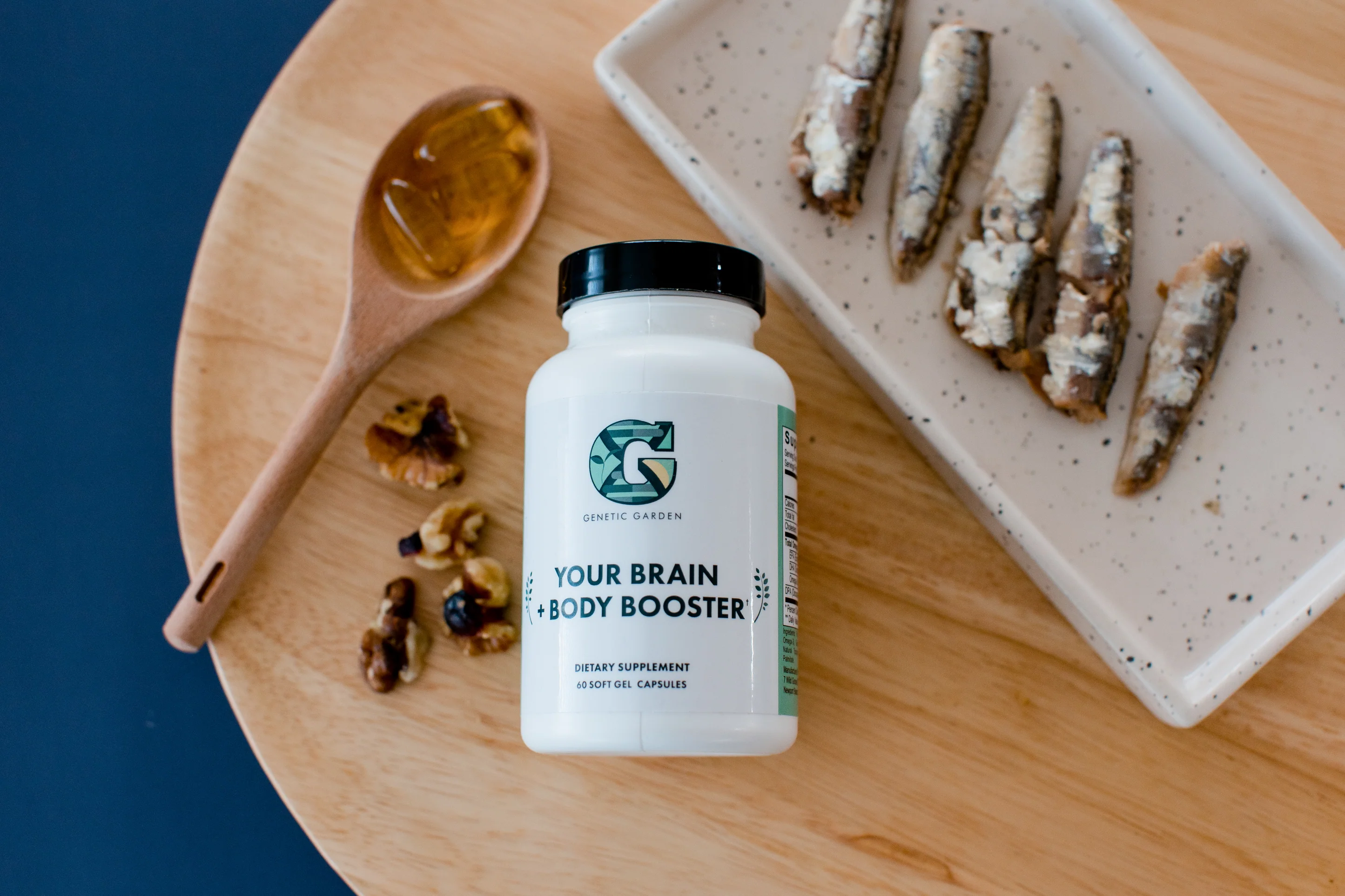Bottle of Your Brain + Body supplement on a table with a wooden spoon, nuts, and sardines.