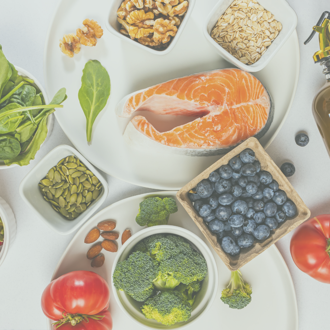 Picture of a white table with blueberries, salmon, broccoli, tomatoes, nuts, and spinach