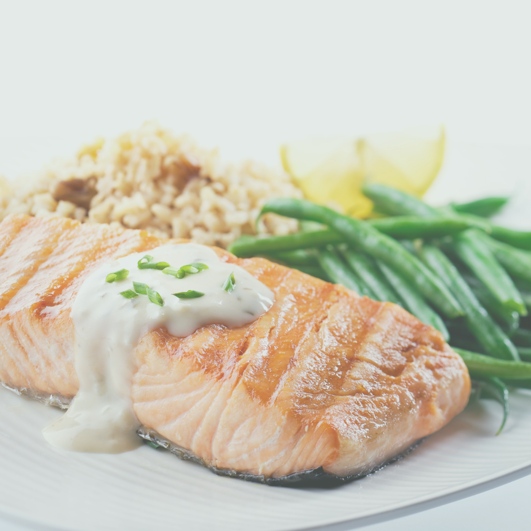 An image of a piece of salmon, asparagus, rice, and a slice of lemon on a plate.